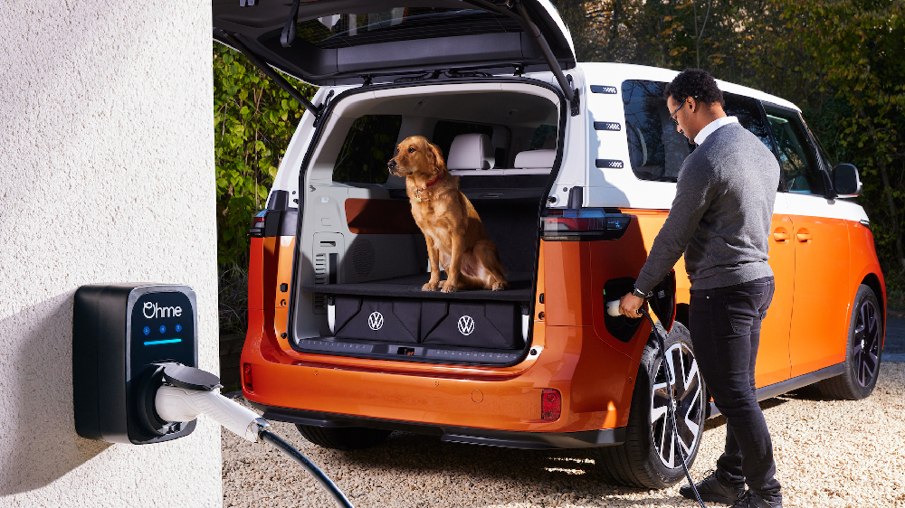 Ohme ePod EV charger installed on a wall with a Volkswagen ID. Buzz charging and a dog sitting in the boot